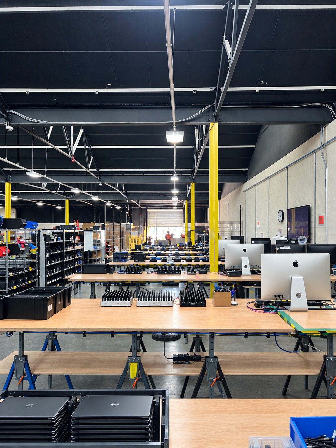 Device charging racks and stacked laptops on the testing benches at Reconome's Rotherham site.
