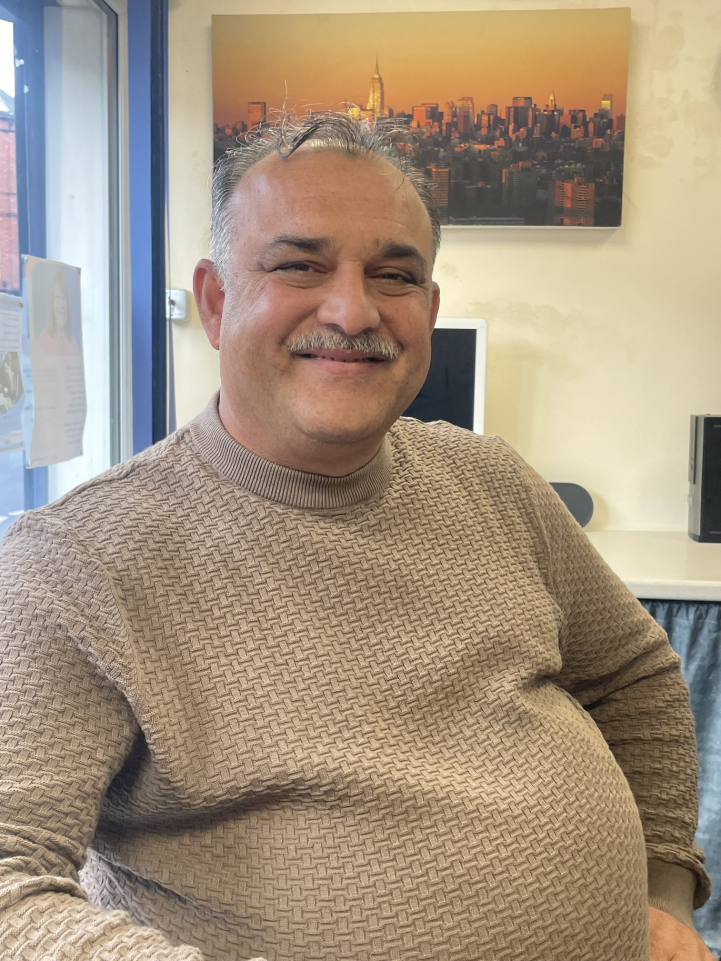 Ahmed smiling while seated indoors.