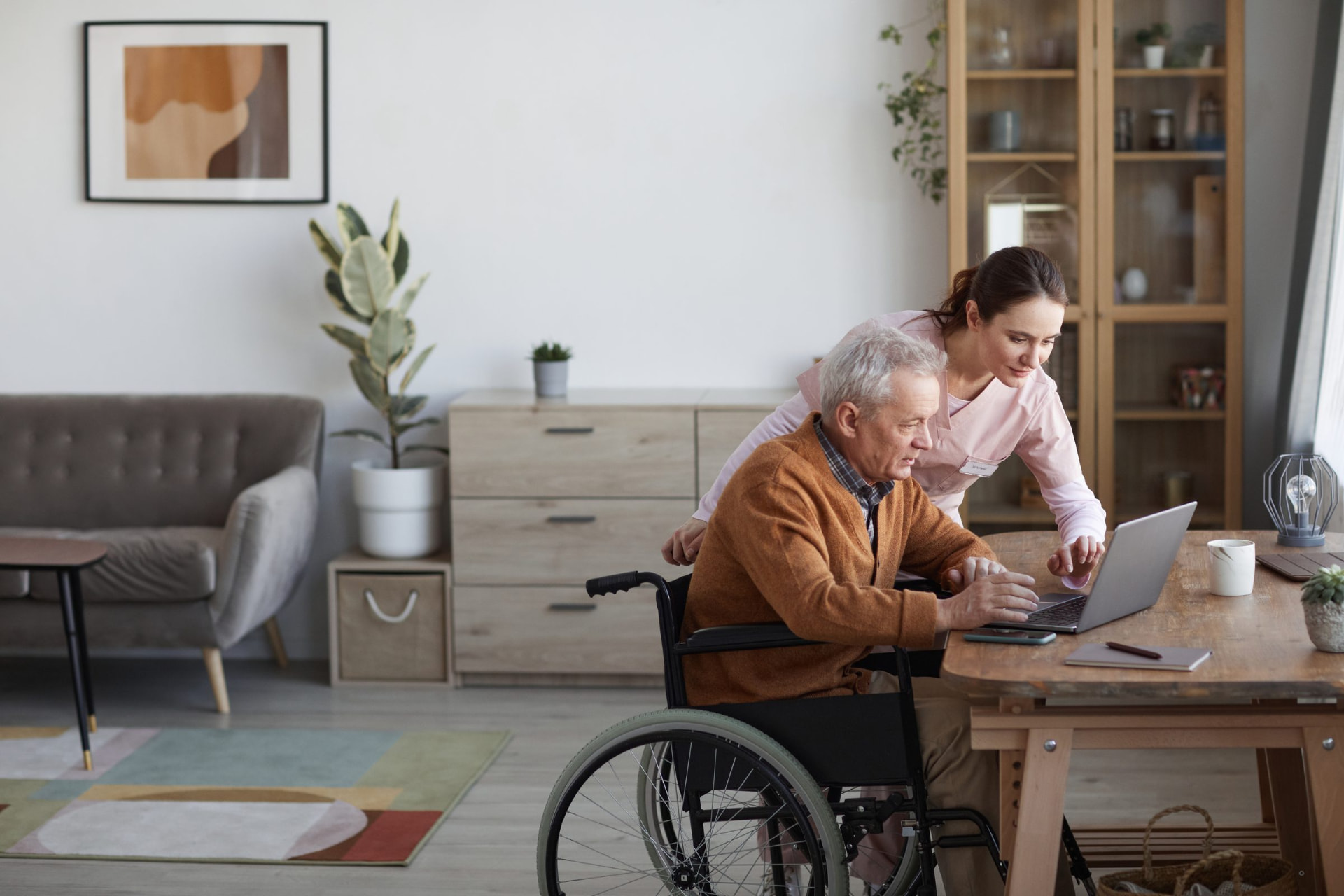 A man opening a refurbished laptop with support from a carer.