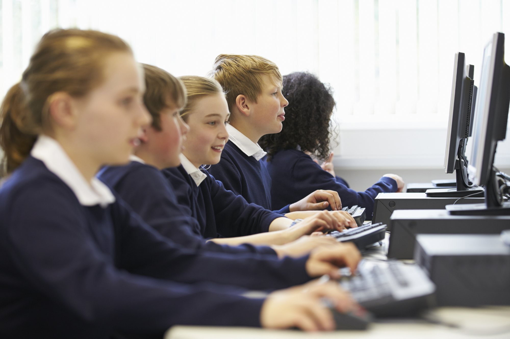School pupils using refurbished desktop computers in a classroom.