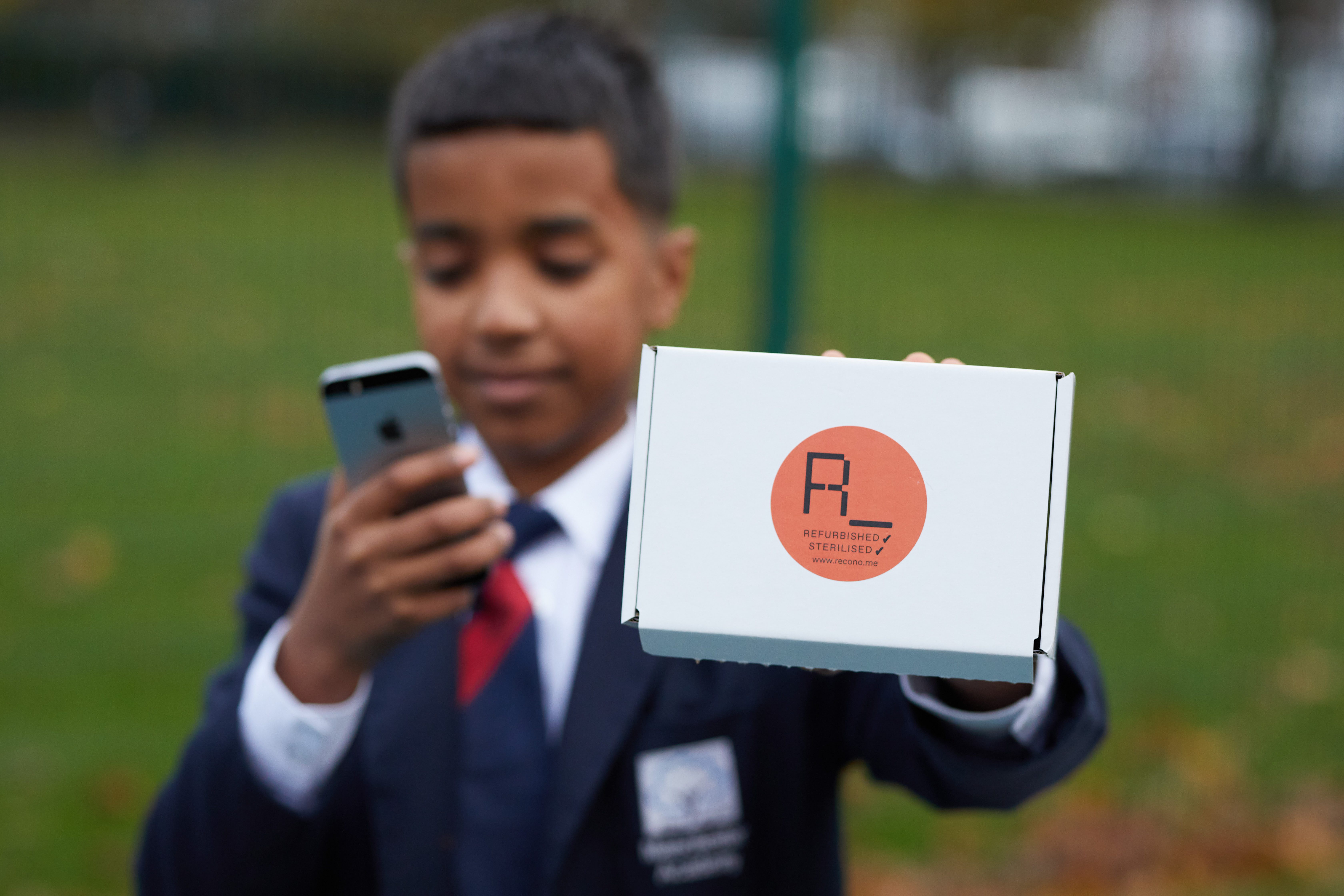 A school boy holding a Refurbished Mobile phone