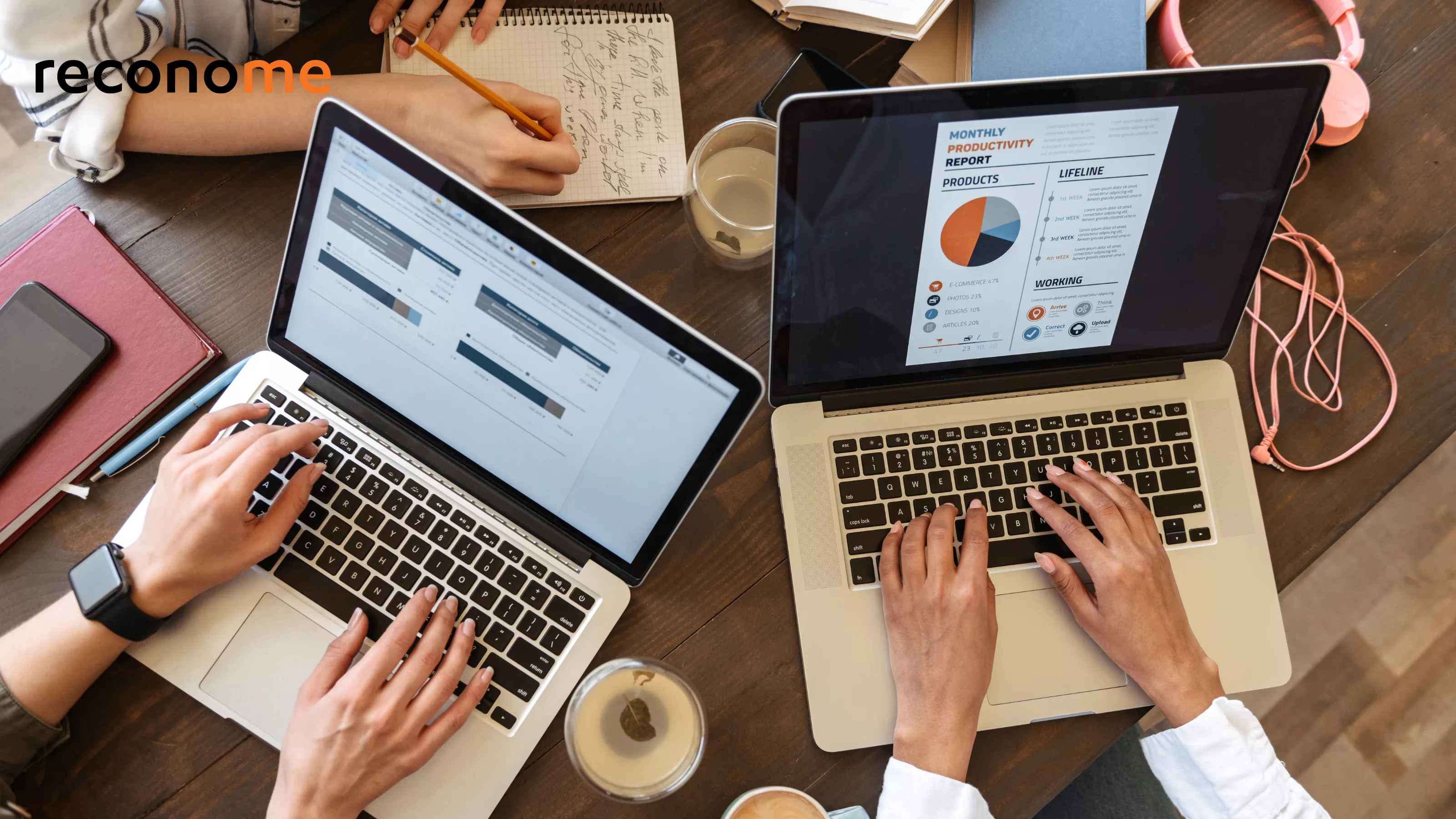 Hands using a laptop at a desk with charts on screen.
