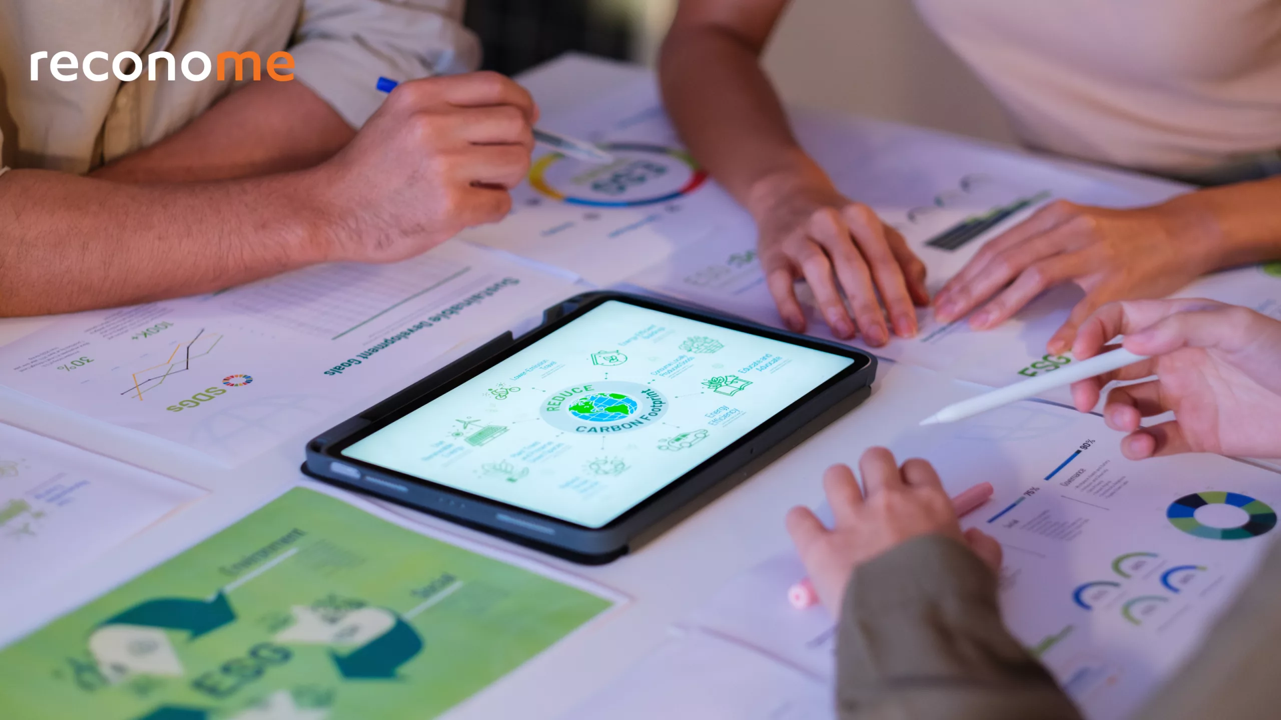 Hands reviewing charts beside a tablet.