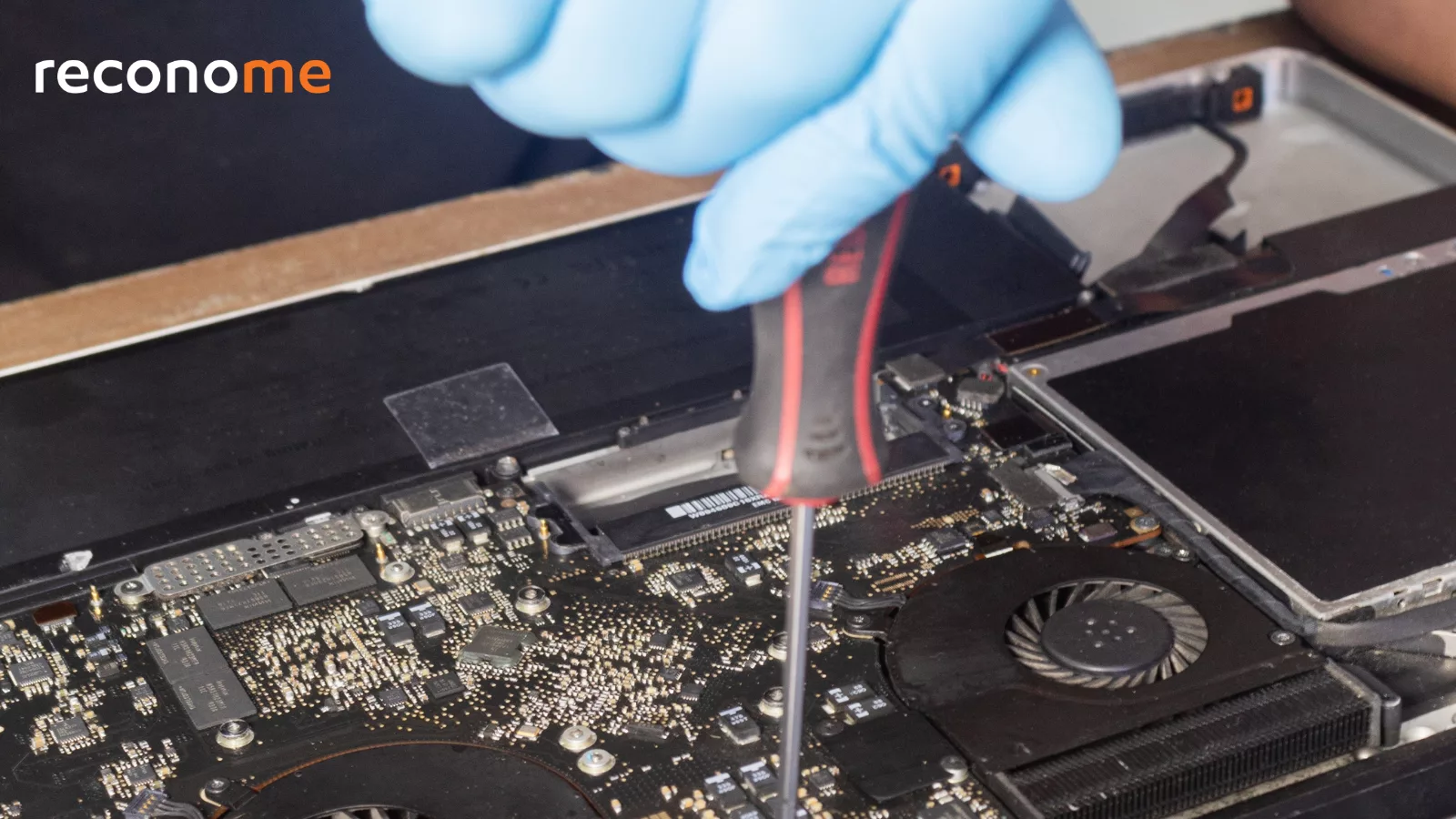 Gloved hands repairing the inside of a laptop.